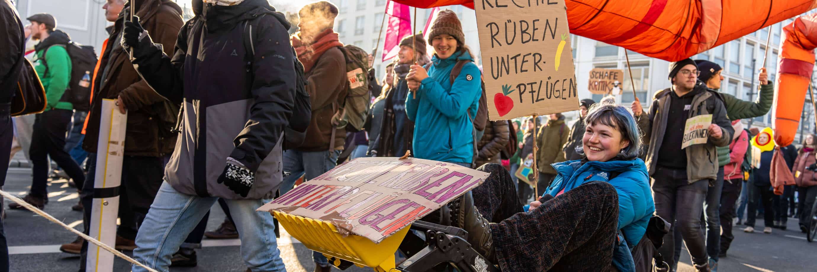 Menschen demonstrieren mit Plakaten und bunter Dekoration.