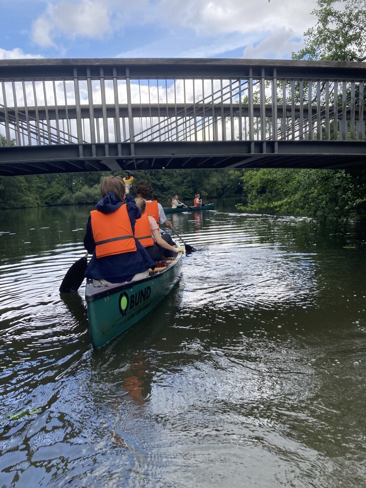 Menschen im Kanu unter Brücke auf Fluss